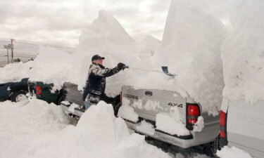 A man clears snow off vehicles after a major nor'easter in 2001 dumped snow across the Northeast.