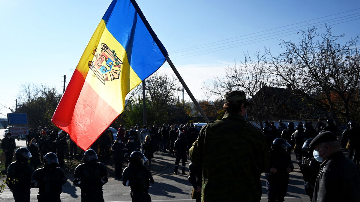 <i>Sergei Gapon/AFP/Getty Images</i><br/>A man holds Moldovan national flag as special police officers patrol a street near a polling station during the second round of Moldova's presidential election in the town of Varnita.