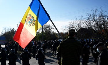 A man holds Moldovan national flag as special police officers patrol a street near a polling station during the second round of Moldova's presidential election in the town of Varnita.