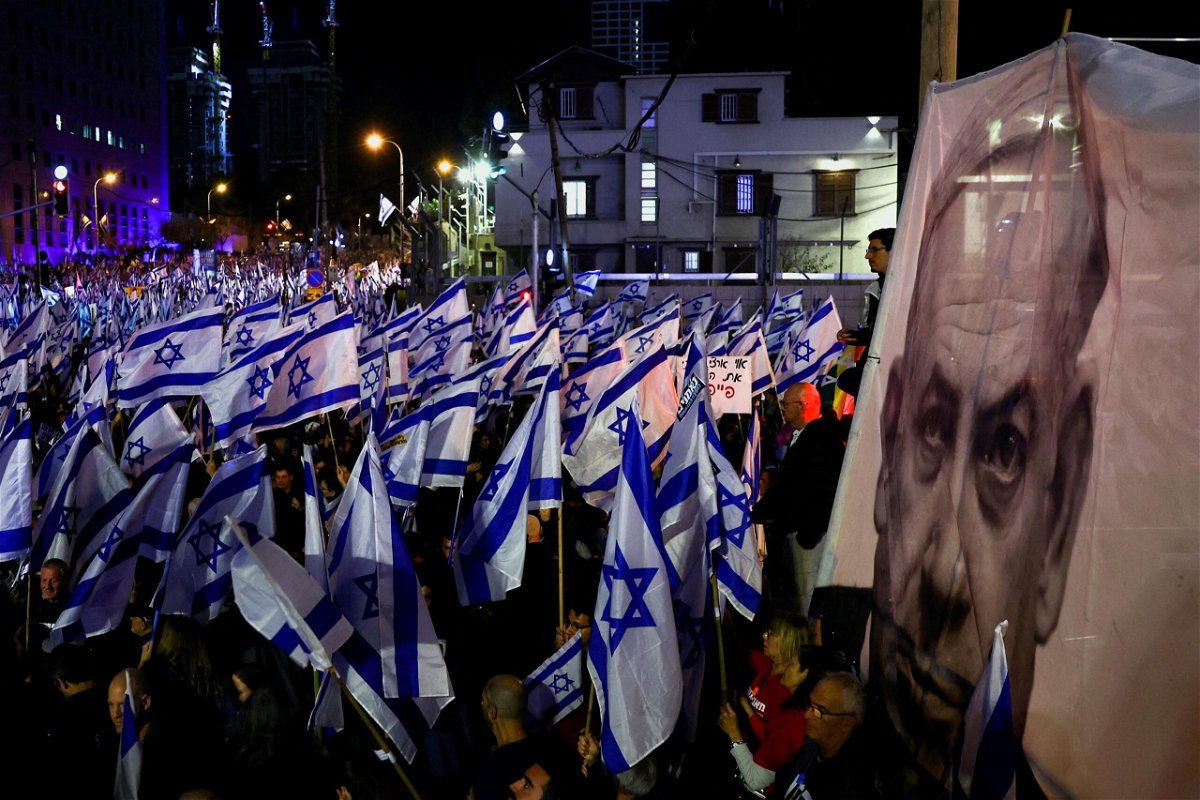 <i>Ronen Zvulun/Reuters</i><br/>Demonstrators hold Israeli flags next to an image of Prime Minister Benjamin Netanyahu in Tel Aviv