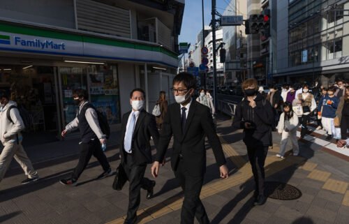 Businessmen walk towards Shinjuku station in Tokyo on March 16