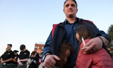 R.T. VanOrden shields his daughters from the wind during a vigil for the victims of a deadly shooting at the Covenant School in Nashville