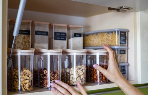 Domestic healthy vegetarian dry food storage organization on shelf at kitchen cupboard. Comfortable neatly keeping arrangement in glass containers oat flakes