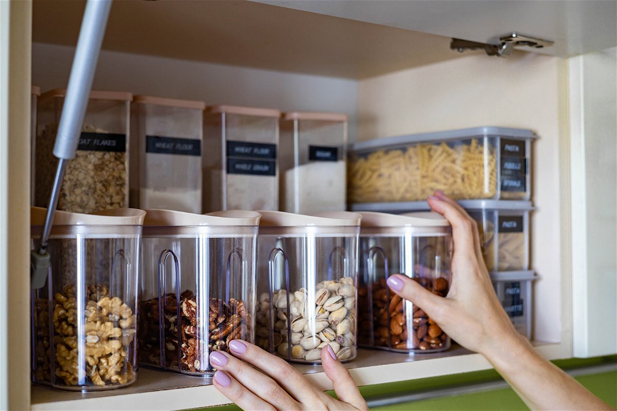 <i>kostikovanata/Adobe Stock</i><br/>Domestic healthy vegetarian dry food storage organization on shelf at kitchen cupboard. Comfortable neatly keeping arrangement in glass containers oat flakes