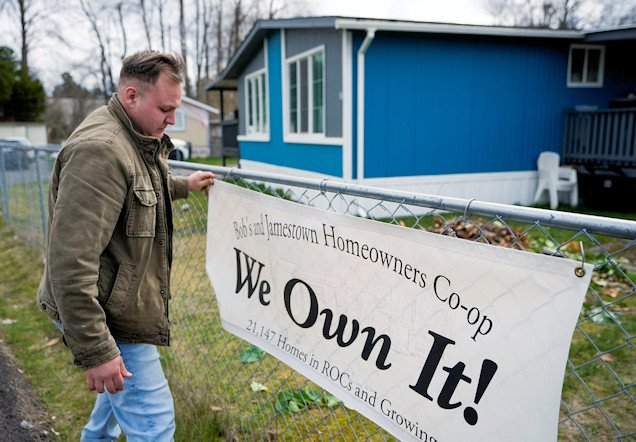 Gadiel Galvez, 22, adjusts a sign stating that his resident cooperative owns their mobile home park, Bob’s and Jamestown Homeowners Cooperative, in Lakewood, Wash.