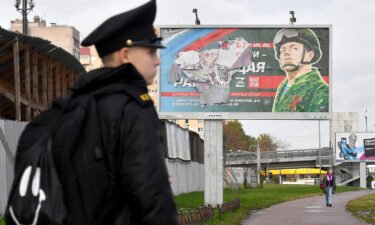 A military cadet stands in front of a billboard promoting contract army service in Saint Petersburg on October 5