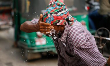 A rickshaw puller splashes water on his face to get relief during a heatwave in Dhaka