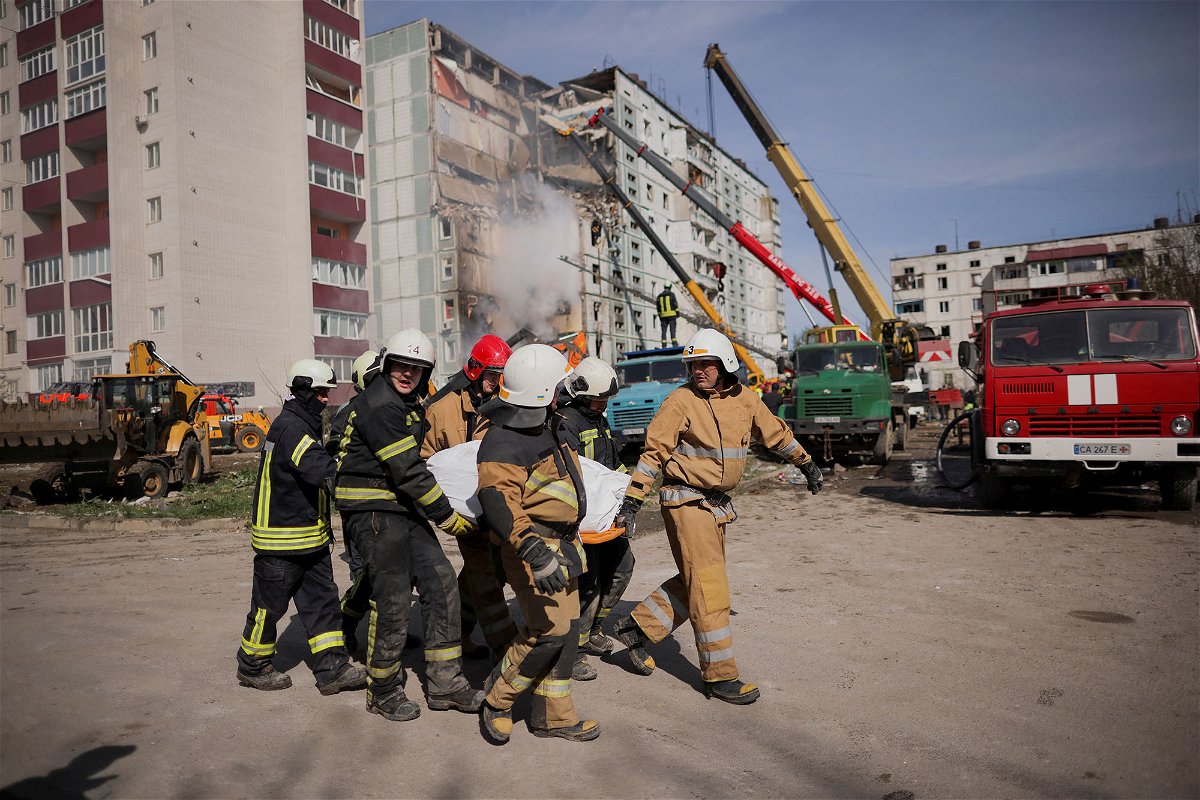 <i>Carlos Barria/Reuters</i><br/>Rescuers carry a body covered with a bag as they work at the site of a heavily damaged residential building hit by a Russian missile