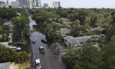 Trucks and a resident on foot make their way through receding floodwaters in the Sailboat Bend neighborhood of Fort Lauderdale