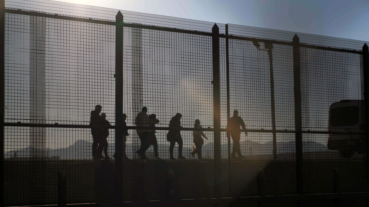 <i>Allison Dinner/AFP/Getty Images</i><br/>A US Border Patrol agent leads migrants who crossed into the US from Mexico to a van for transportation in El Paso