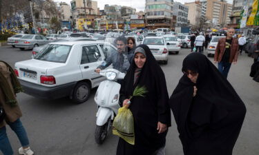 A veiled Iranian woman walks along a square with her relative in northern Tehran on March 17.