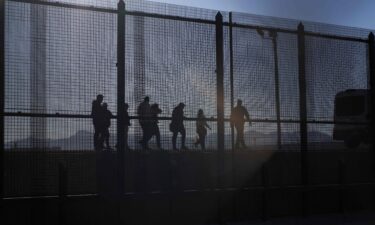 A US Border Patrol agent leads migrants who crossed into the US from Mexico to a van for transportation in El Paso