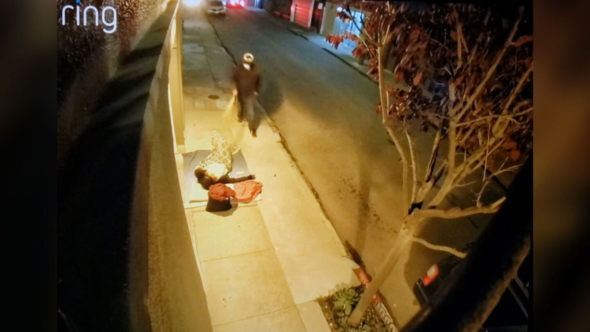 <i>Courtesy San Francisco Public Defender's Office</i><br/>A still from a November 2021 video shows an unidentified assailant who comes upon a sleeping homeless person on the sidewalk and bear sprays them in the face for several seconds before walking away