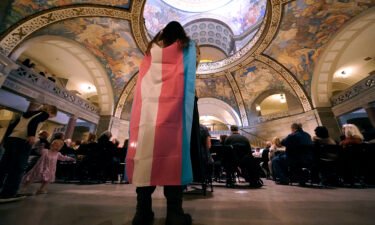 Glenda Starke wears a transgender flag as a counterprotest during a rally in favor of a ban on gender-affirming health care legislation on March 20