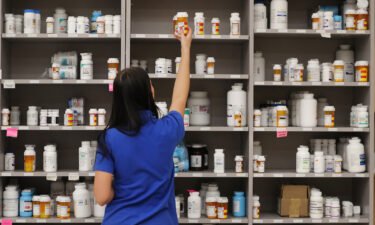 A pharmacy technician grabs a bottle of drugs off a shelve at a pharmacy in Midvale