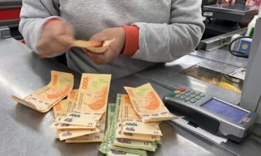 A cashier counts Argentine pesos bills at a supermarket in Buenos Aires