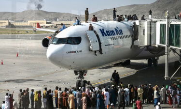 Afghans climb atop a plane as they wait at the Kabul airport on August 16