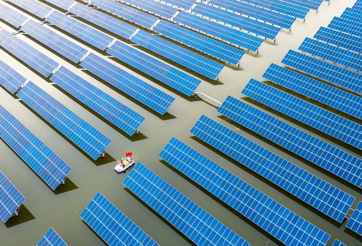 <i>Song Weixing/VCG/Getty Images/FILE</i><br/>Workers check solar panels installed atop a fish pond at a hybrid power station in May 2022 in China's central province of Anhui.