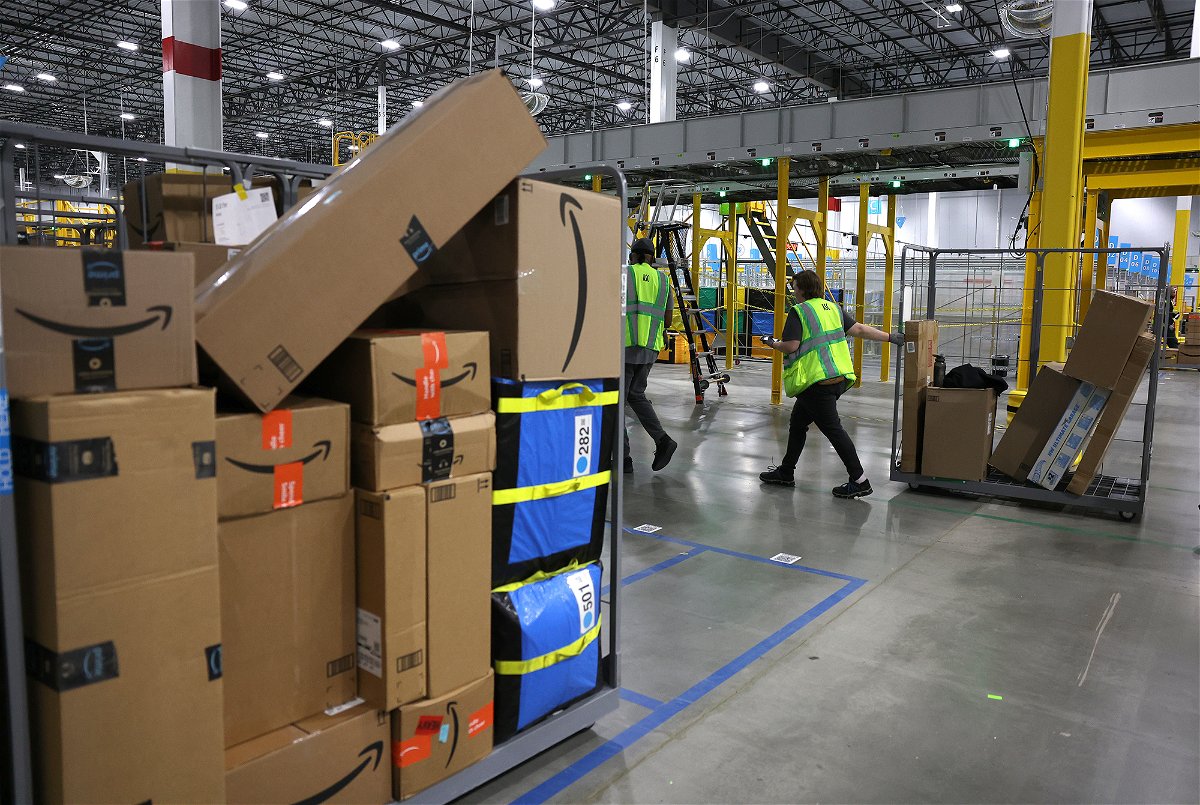 <i>Justin Sullivan/Getty Images</i><br/>An Amazon worker moves a cart filled with packages at an Amazon delivery station in November 2022 in Alpharetta