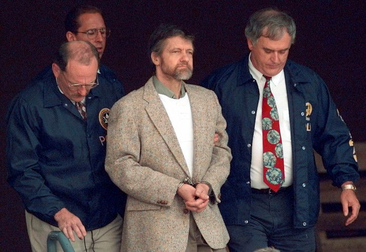 Theodore Kaczynski looks around as U.S. Marshals prepare to take him down the steps at the federal courthouse to a waiting vehicle on June 21, 1996, in Helena, Montana