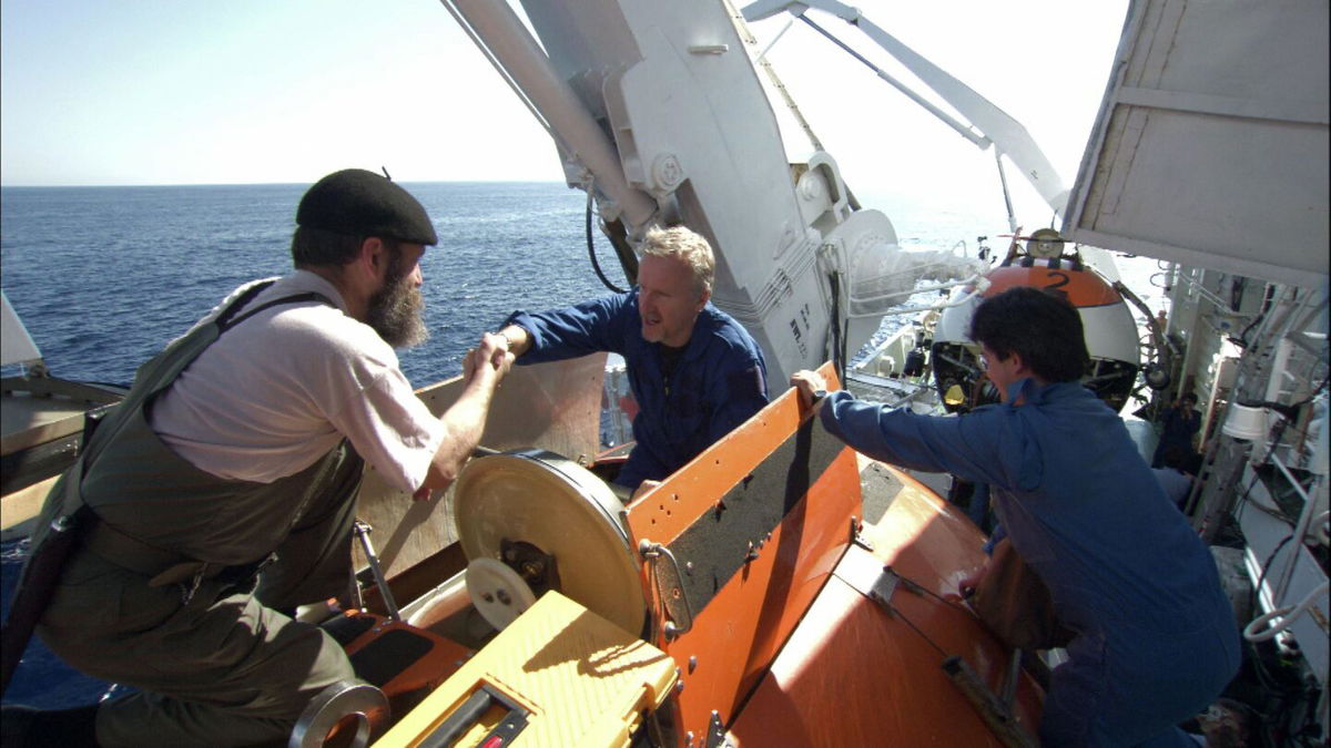 <i>Earthship Prods/Kobal/Shutterstock</i><br/>MIR crew members help James Cameron (center) into MIR 1 during the filming of Cameron's documentary 