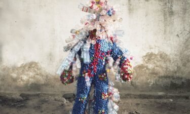Artist Junior Mungongu wears a costume made out of plastic bottles and lids.