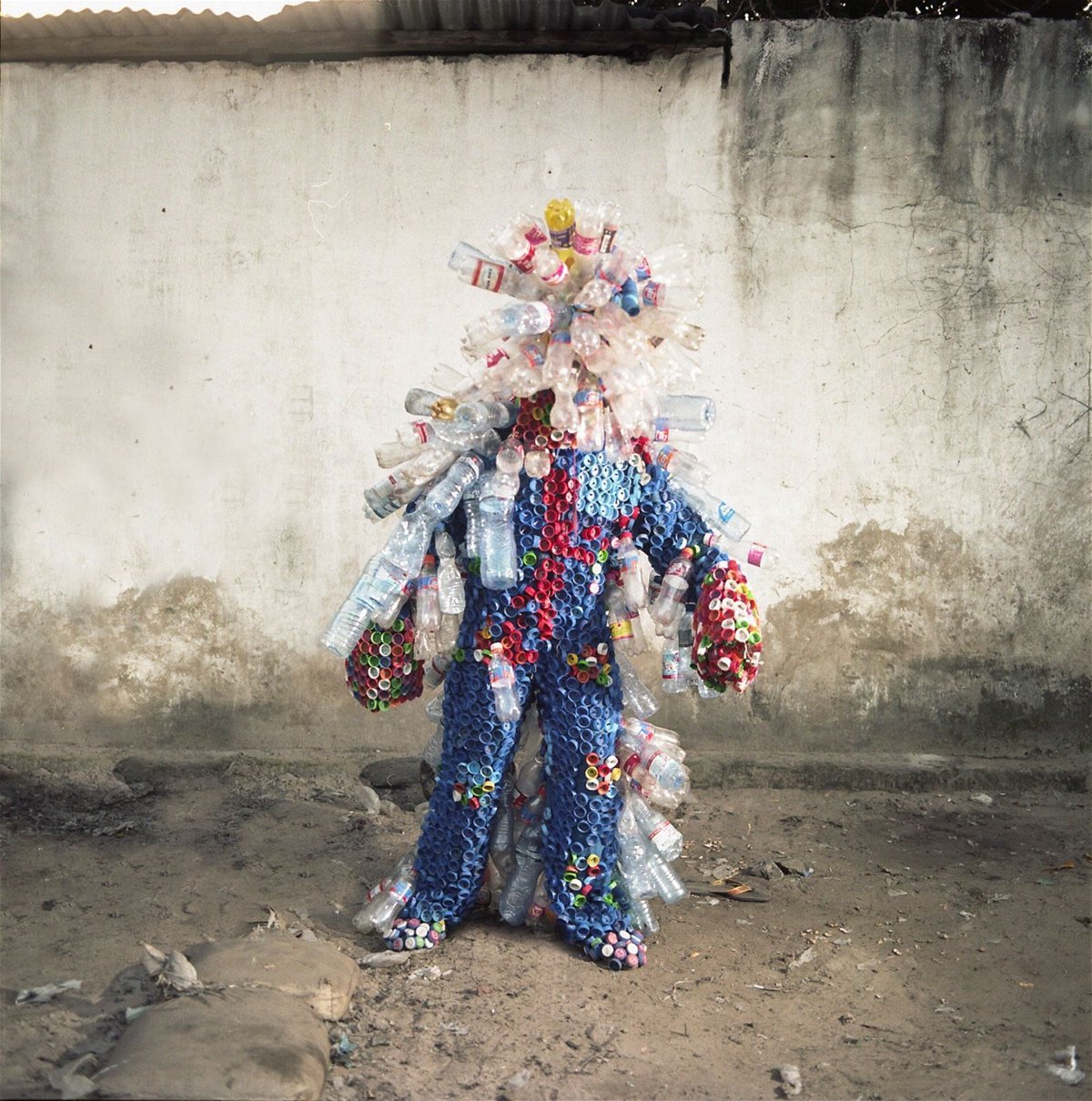 <i>Colin Delfosse</i><br/>Artist Junior Mungongu wears a costume made out of plastic bottles and lids.