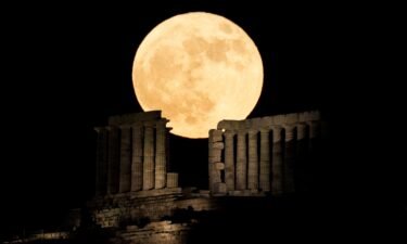 The full strawberry moon rises behind the Temple of Poseidon at Cape Sounion near Athens