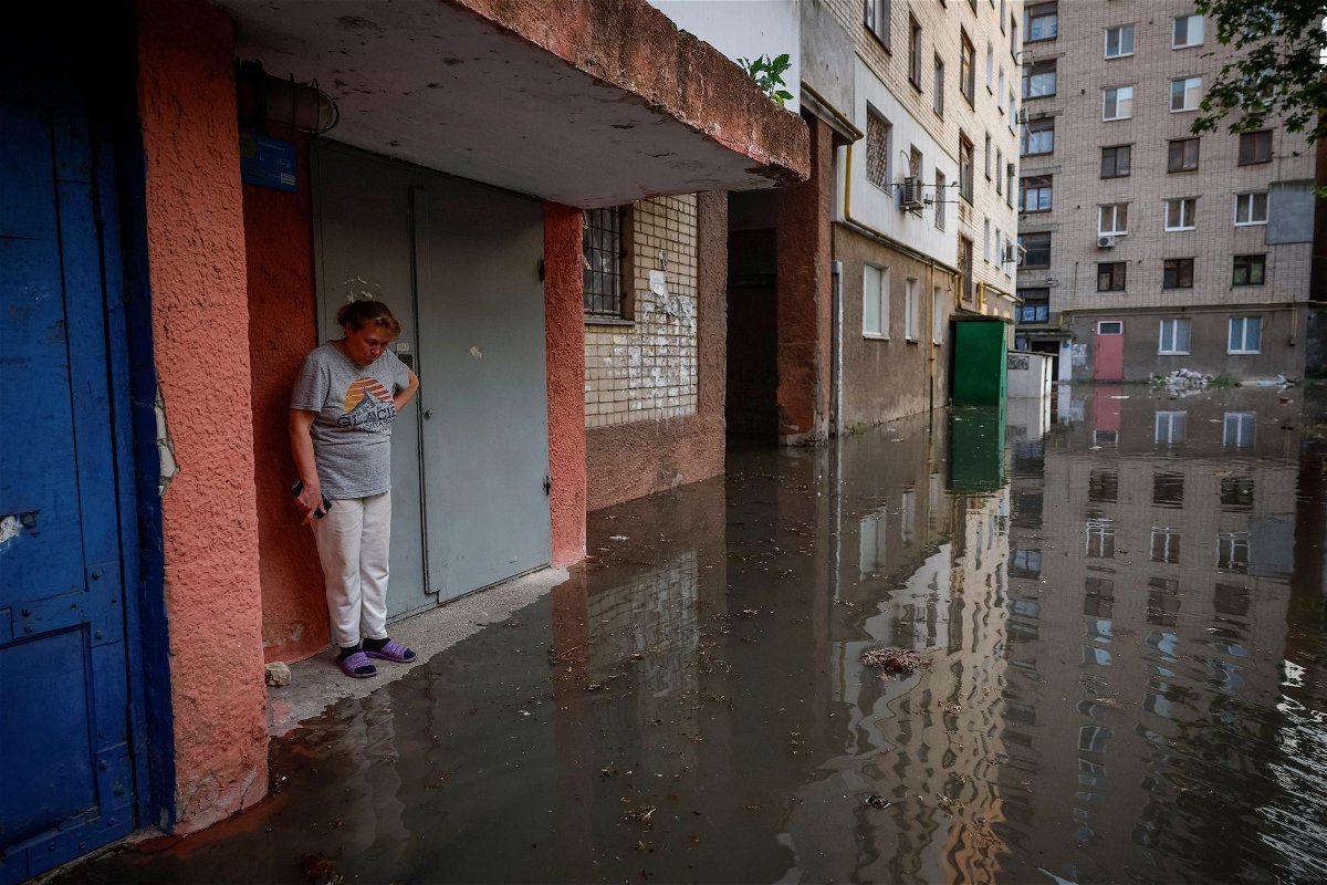 <i>Alina Smutko/Reuters</i><br/>Olena stands next to the entrance to her house on a flooded street