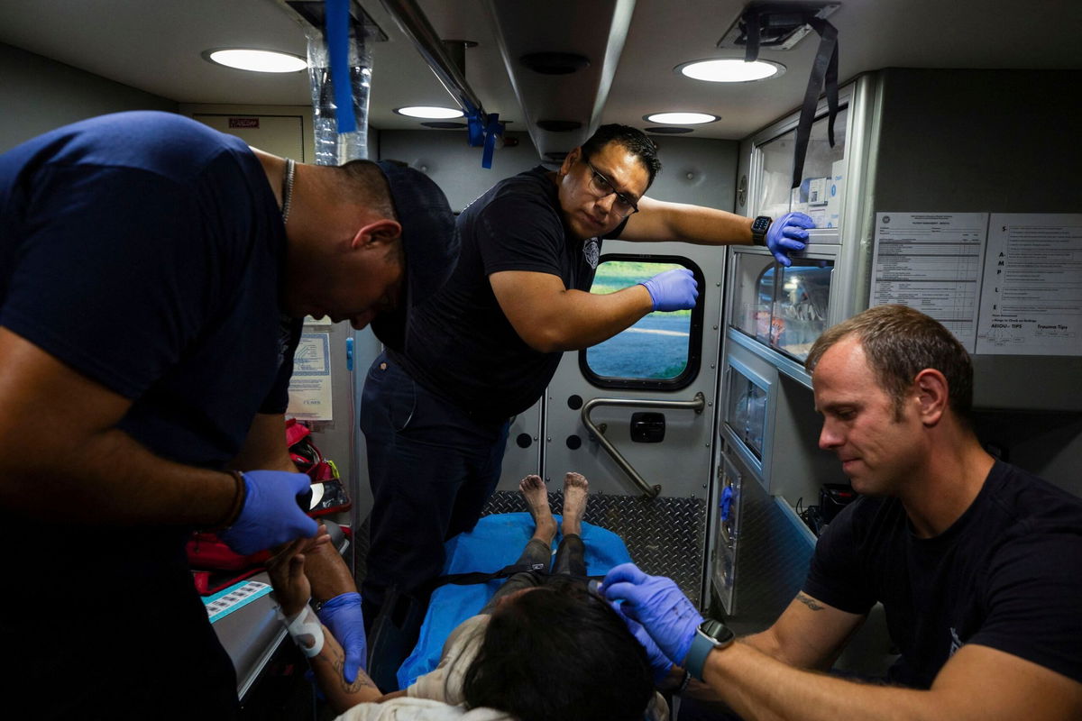 <i>Kaylee Greenlee Beal/Reuters</i><br/>Firefighter EMTs treat a migrant woman suffering from heat exhaustion in the border community of Eagle Pass