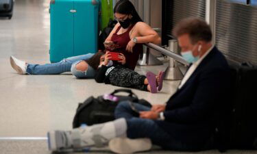 A woman and child wait for their flight alongside another traveler at Miami International Airport on Monday
