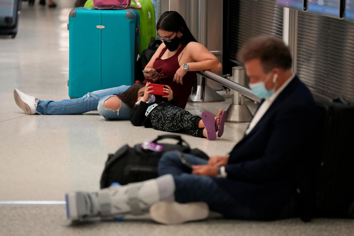 <i>Rebecca Blackwell/AP</i><br/>A woman and child wait for their flight alongside another traveler at Miami International Airport on Monday