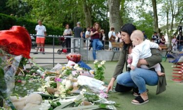 People lay flowers near the scene at a lakeside park in Annecy