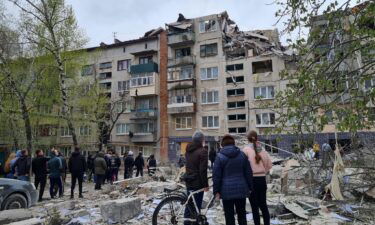 Local residents stand next to an apartment building damaged by a Russian military strike in Sloviansk