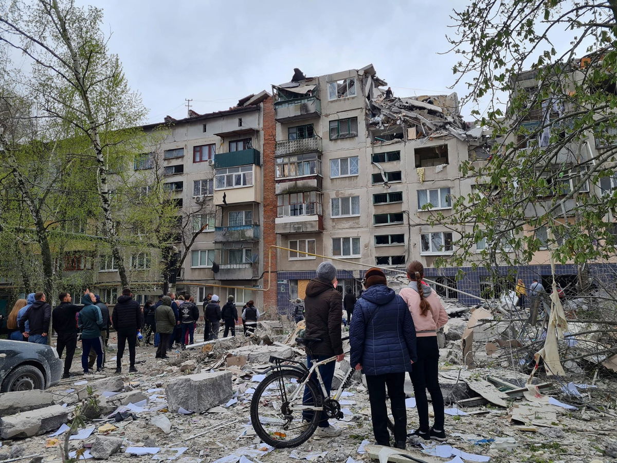 <i>Press service of the Donetsk Regional Military-Civil Administration/Handout/Reuters</i><br/>Local residents stand next to an apartment building damaged by a Russian military strike in Sloviansk