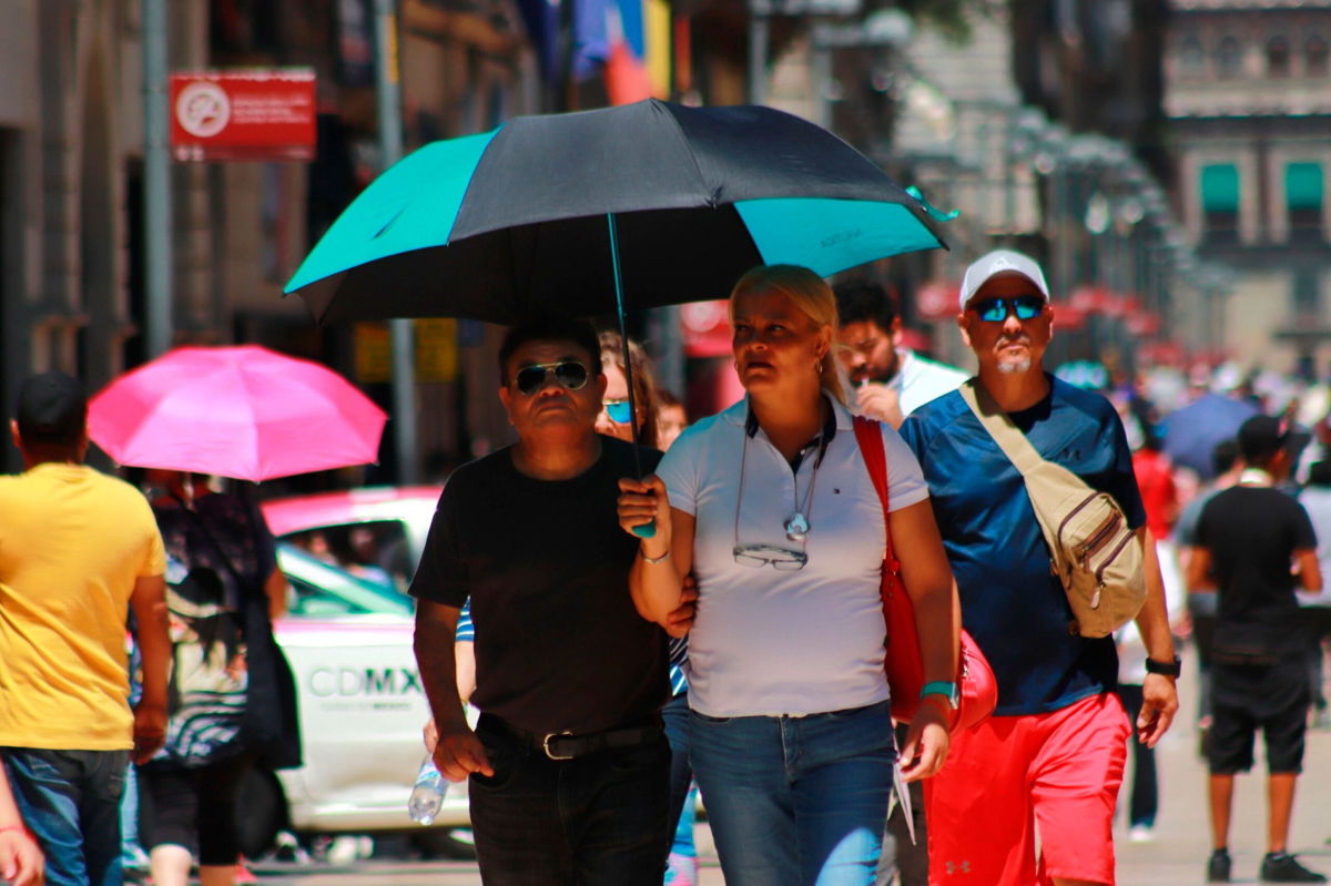 <i>Carlos Santiago/Eyepix Group/Avalon/dpa/Sipa USA</i><br/>People protect themselves from the sun with umbrellas amid high temperatures in Mexico on June 22.