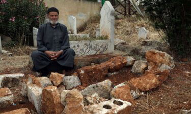 Mohammed Hassan Masto sits next to the grave of his brother Lutfi