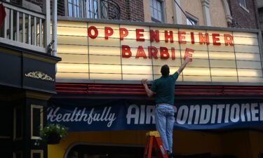 An employee adds letters for upcoming film releases "Oppenheimer" and "Barbie" to a marquee at the Colonial Theater on July 16