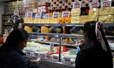 Women buy cheese in a stall at the Central Market in Buenos Aires