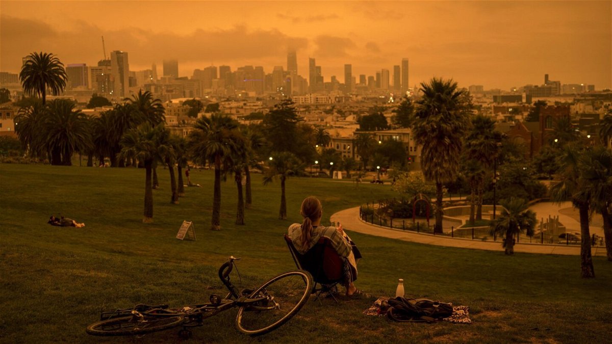 <i>David Paul Morris/Bloomberg/Getty Images</i><br/>A person sits in Delores Park as smoke and fog hang over the skyline in San Francisco