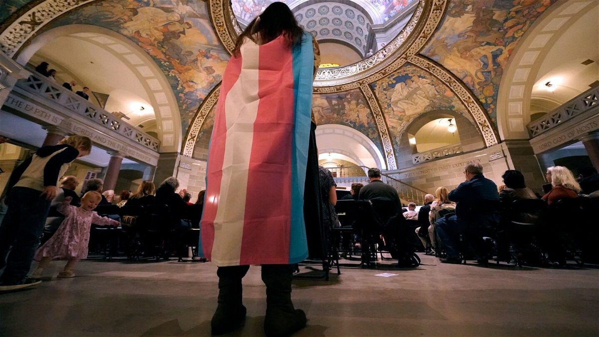 <i>Charlie Riedel/AP</i><br/>Glenda Starke wears a transgender flag as a counter protest during a rally in favor of a ban on gender-affirming health care legislation