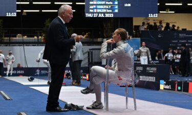 An official of the International Fencing Federation (FIE) speaks Smirnova as she sits on the fencing strip.