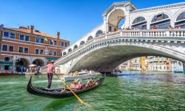 A gondola packed with tourists goes under the Rialto Bridge on the Grand Canal in Venice.
