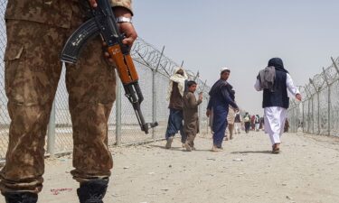 A Pakistani soldier stands guard as stranded Afghan nationals return to Afghanistan at the Pakistan-Afghanistan border crossing point in Chaman on August 15