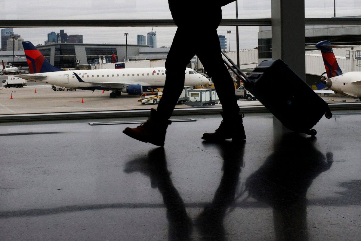 <i>Brian Snyder/Reuters/FILE</i><br/>A passenger walks past a Delta Airlines plane at a gate at Logan International Airport in Boston