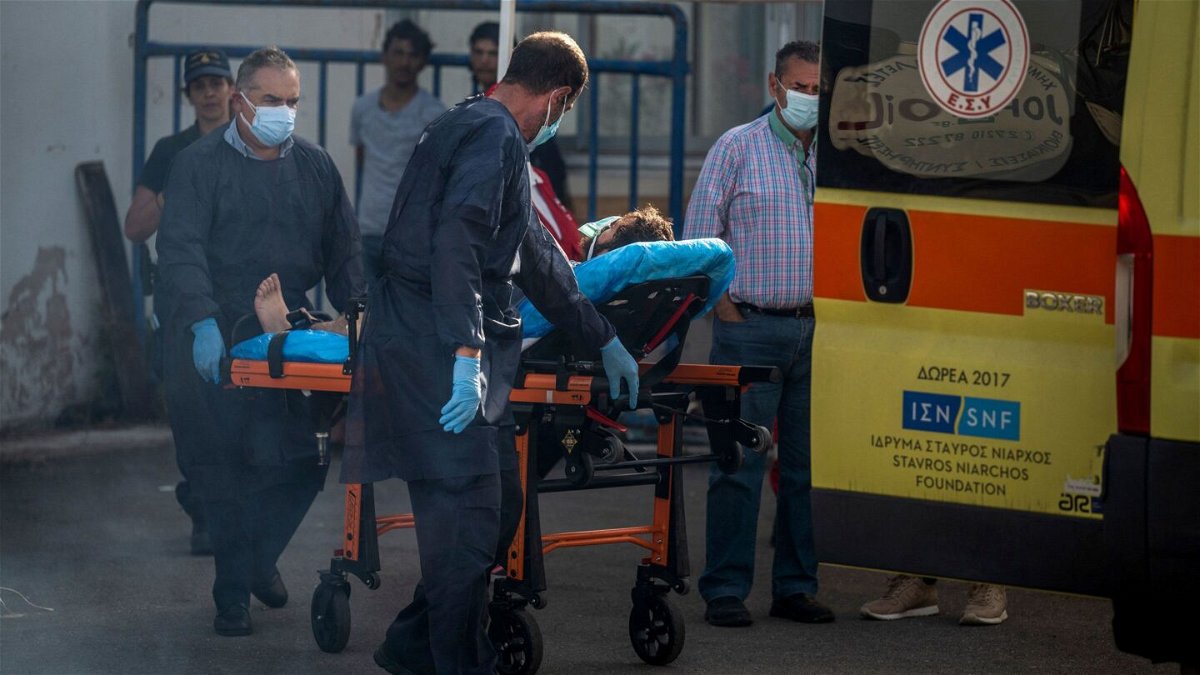 <i>Angelos Tzortzinis/AFP/Getty Images</i><br/>Medical staff carry a survivor on a stretcher outside a warehouse at the port in Kalamata town