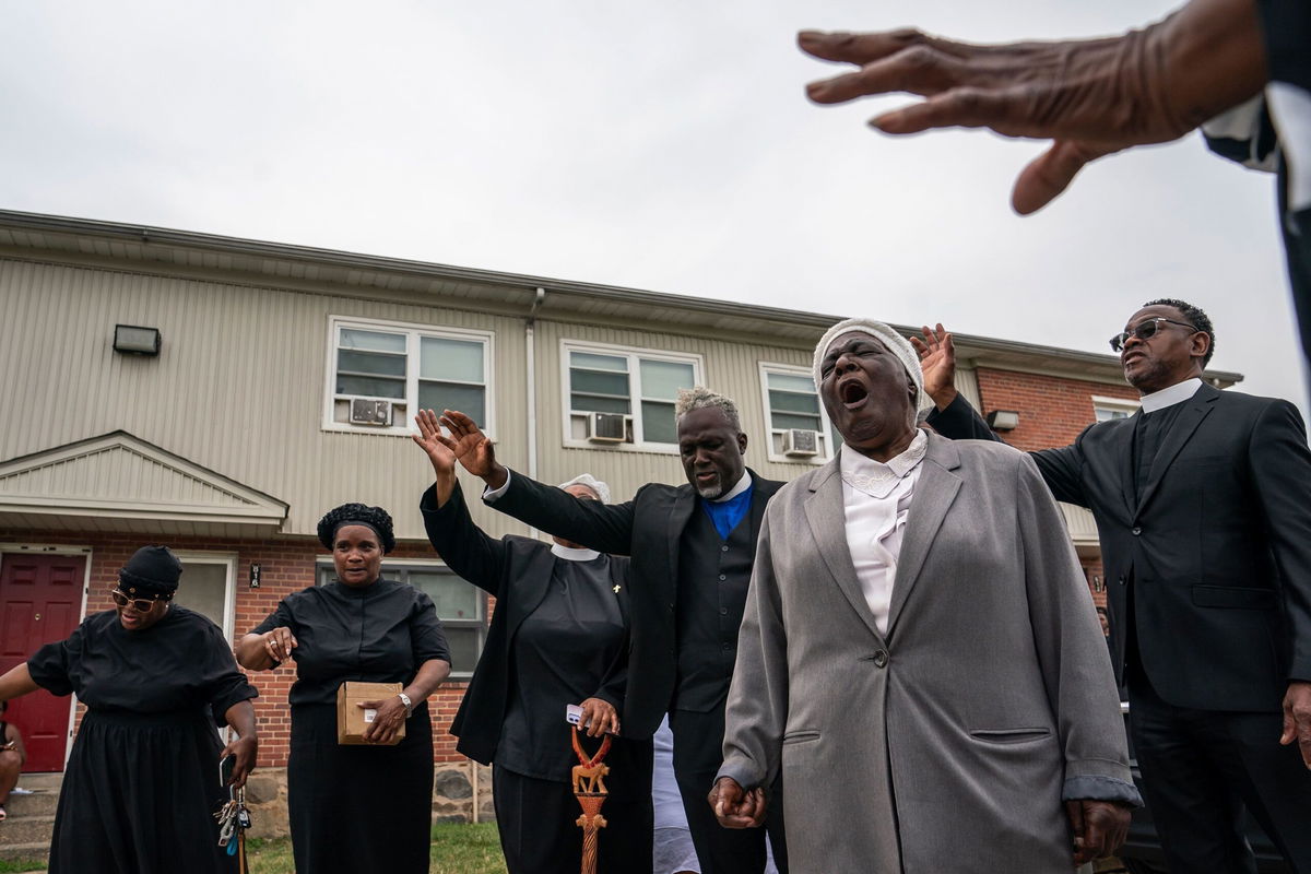 <i>Nathan Howard/Getty Images</i><br/>Members of the Kingdom Life Church pray at the site of a mass shooting in the Brooklyn Homes neighborhood on July 2.