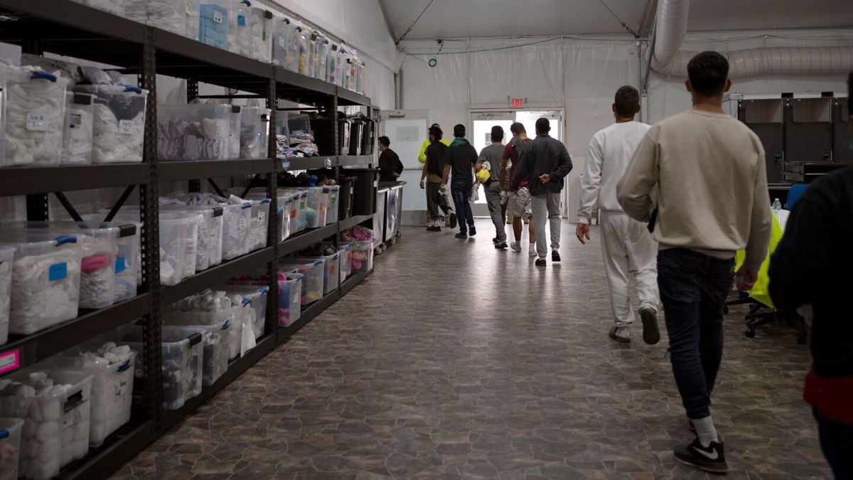 <i>Danielle Villasana/The Washington Post/Getty Images</i><br/>Migrants walk through a newly opened U.S. Customs and Border Protection soft-sided facility in El Paso