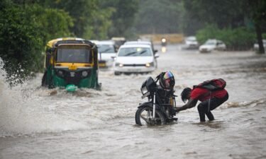 Commuters move through flooded streets after heavy rains in New Delhi on July 9