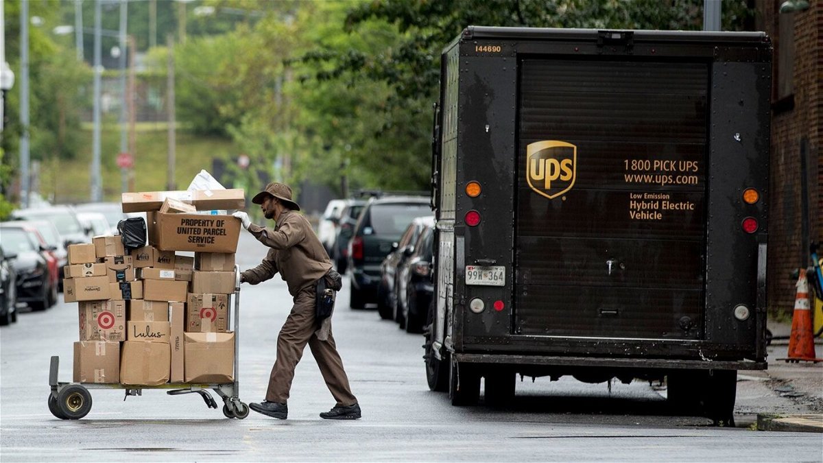 <i>Andrew Harnik/AP/FILE</i><br/>A delivery man pushes a cart full of packages to deliver to an apartment building.